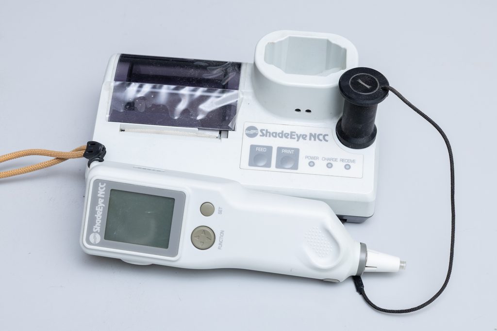 歯科用測色器「ShadeEye NCC」の全体写真。歯の色を数値化して精密に測定する手持ち式の測定測定子と、ドック付きのベースユニットが写っている機器画像。